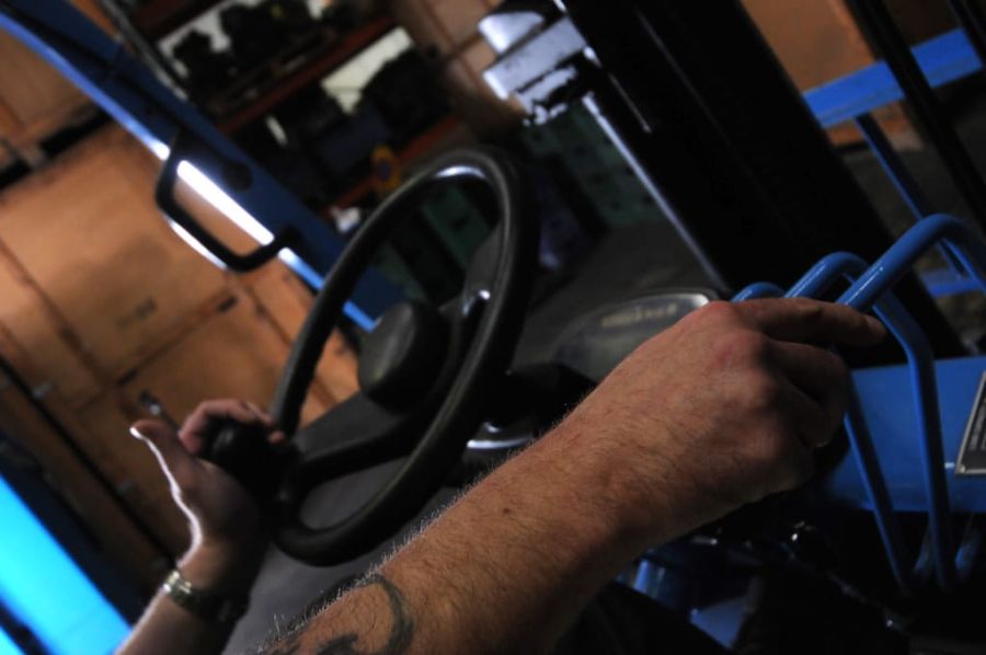 Operator's hands on the steering wheel and hydraulic levers